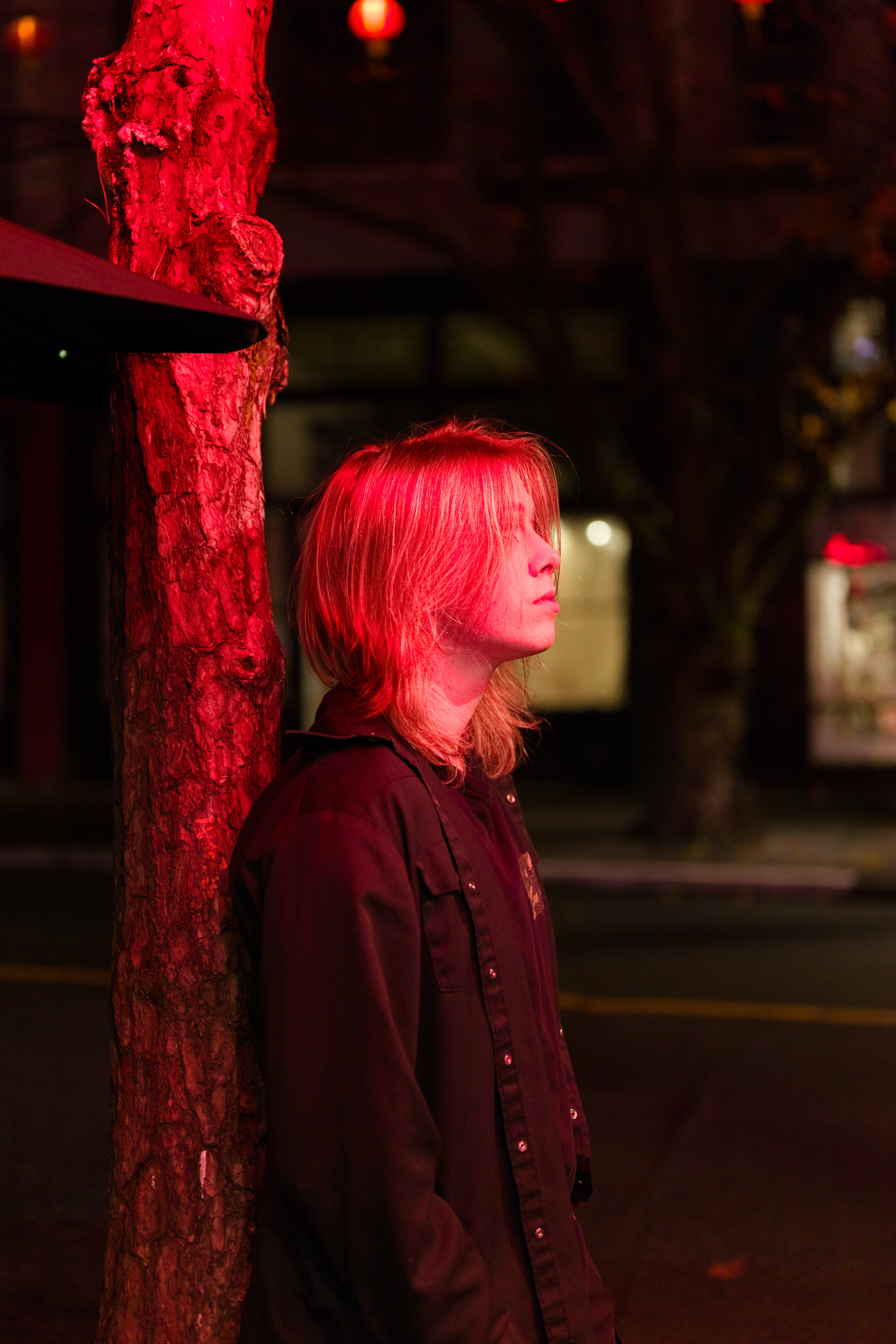 a person leaning against a tree under a red light